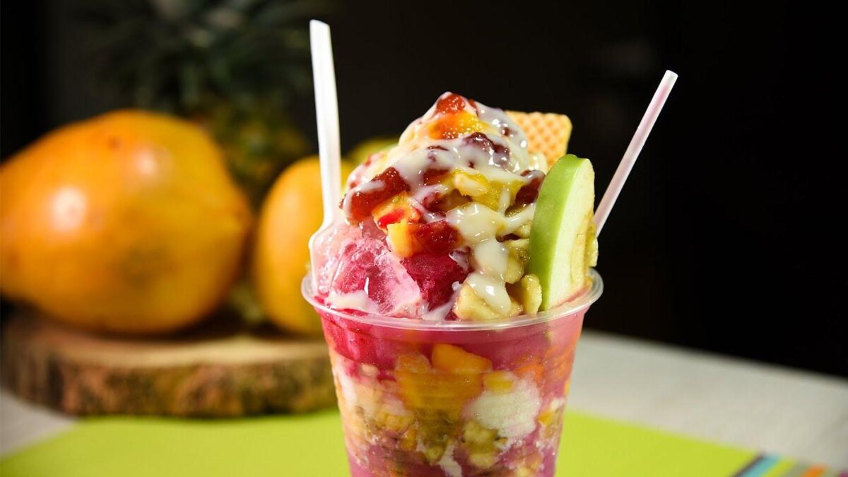 Vaso de cholado con hielo raspado, frutas, leche y galleta