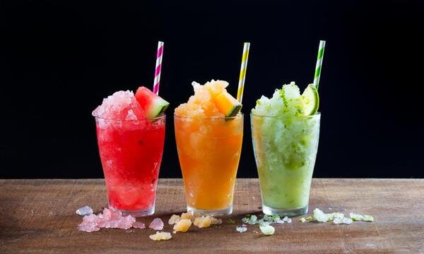 Tres granizados de colores servidos en vaso, con pajilla